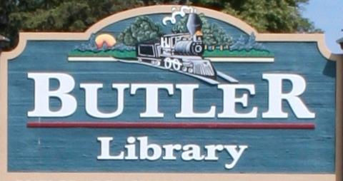 Outdoor sign featuring the words "Butler Library" and an image of a train on a blue background